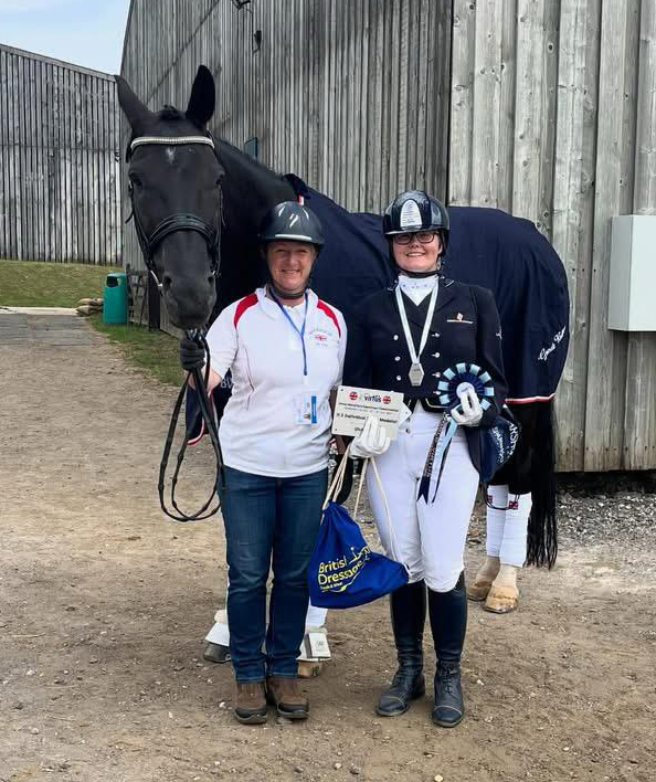 two riders standing with a horse