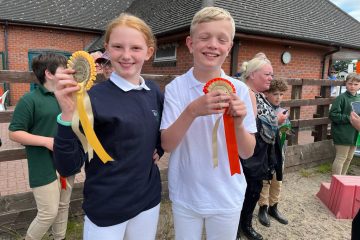 a girl and boy displaying their prize ribbons